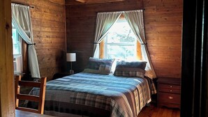 Une chambre dans une cabane en bois, avec un lit, un bureau et une chaise.