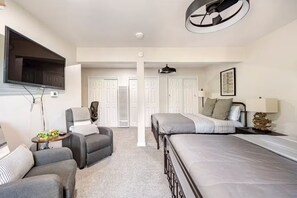 Un dormitorio con cama, escritorio, silla, televisor y puerta.