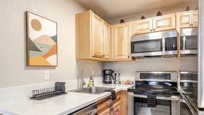 A modern kitchen with wooden cabinets, stainless steel appliances, a white countertop, and a skylight. - Tahoe Mountain Escape. 12 Min to Beach (Stateline)