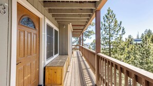 A wooden deck with a bench, a door with a window, and a view of trees. - Tahoe Mountain Escape. 12 Min to Beach (Stateline)