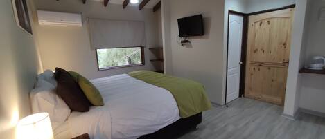 Una camera da letto con un letto, una televisione, una finestra e una porta in legno.