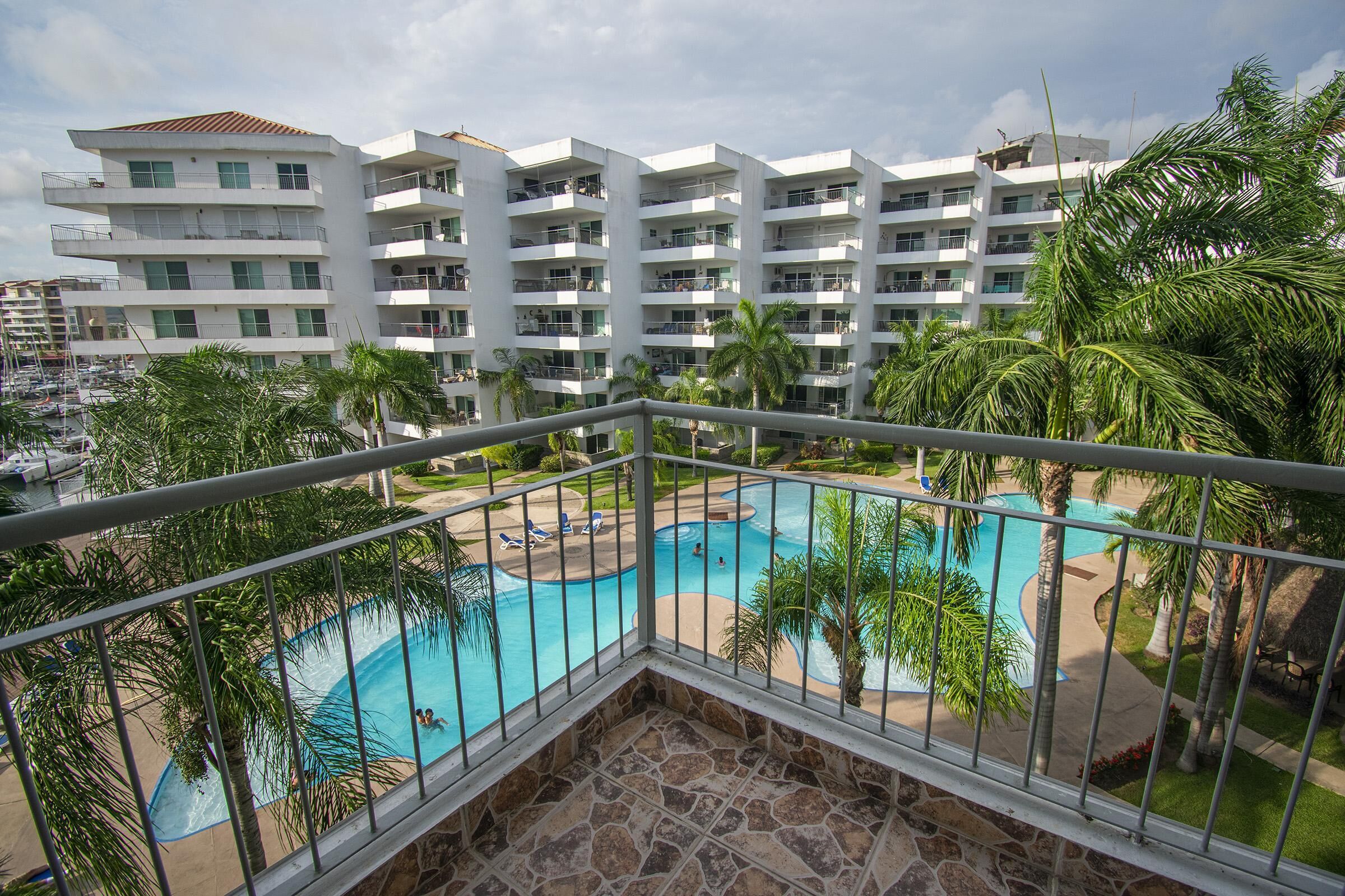 Un hôtel doté d’une piscine, de plusieurs balcons et de palmiers.