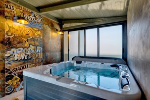 A hot tub in a room with a graffiti wall and large windows. - Villa Pieron - Luxury Spa Oasis (Marcana)