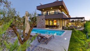 A modern two-story house with a swimming pool, outdoor furniture, and a well-maintained garden. - Villa Bavigo - Luxury Spa Oasis (Marcana)