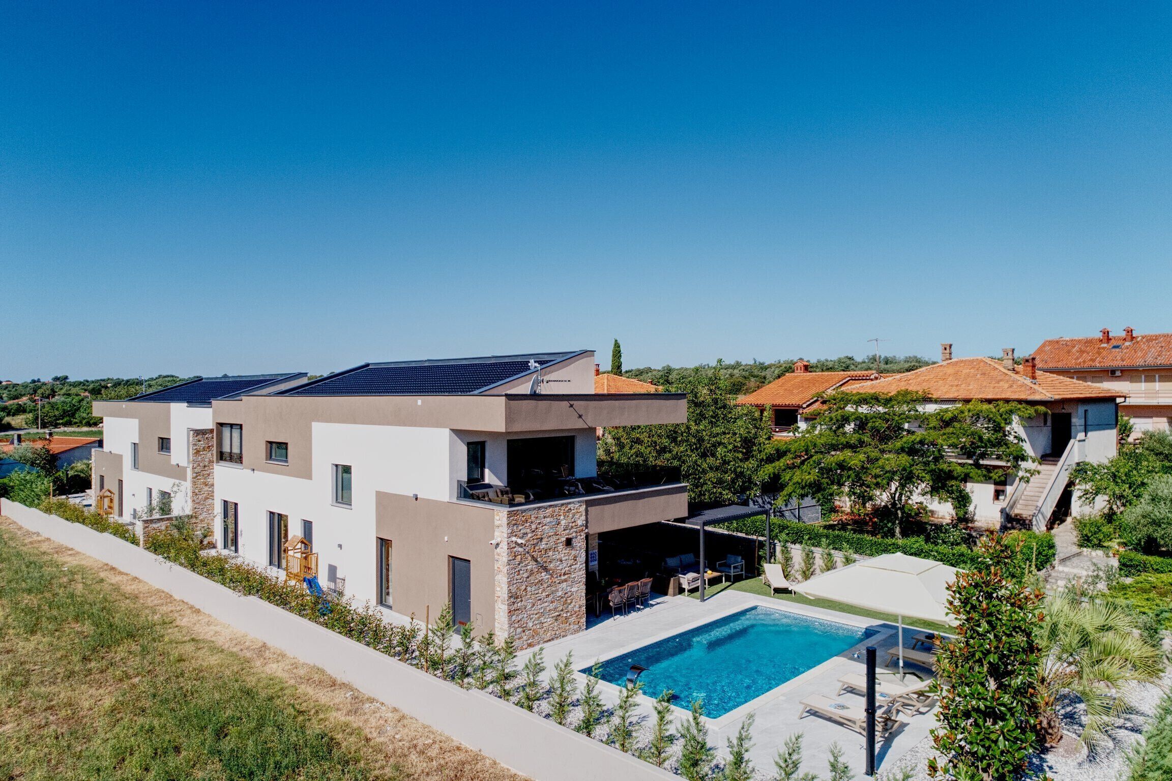 Ein moderner Wohnkomplex mit Solaranlage, Schwimmbad und überdachter Außenbereich.