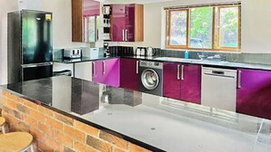 A kitchen with a brick counter, a washing machine, and a refrigerator. - 5 bedroom accommodation in Grantham (Grantham)
