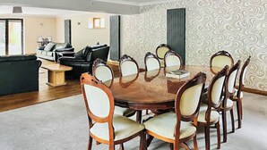 A dining room with a round table and chairs, a sofa, and a patterned wall. - 5 bedroom accommodation in Grantham (Grantham)
