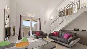 A modern living room with a sofa, two chairs, a dining table with a bowl, and a staircase. - Sea View Vacation at Apartment Jana - Cres Island (Cres)