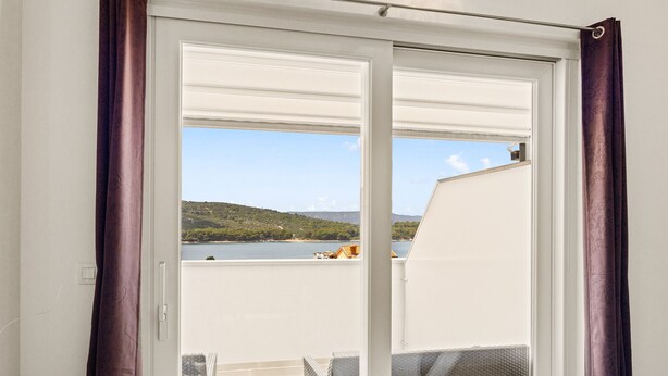 A balcony with a view of a lake and hills, a white door, and purple curtains. - Sea View Vacation at Apartment Jana - Cres Island (Cres)