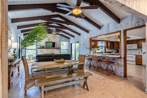 A spacious living area with a wooden dining table, a sofa, and a large plant.