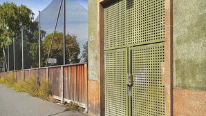 A building with a large metal gate and a fenced area with a tall structure in the background. - DOWNToWN KING BED FASHiONABLE (Oslo)