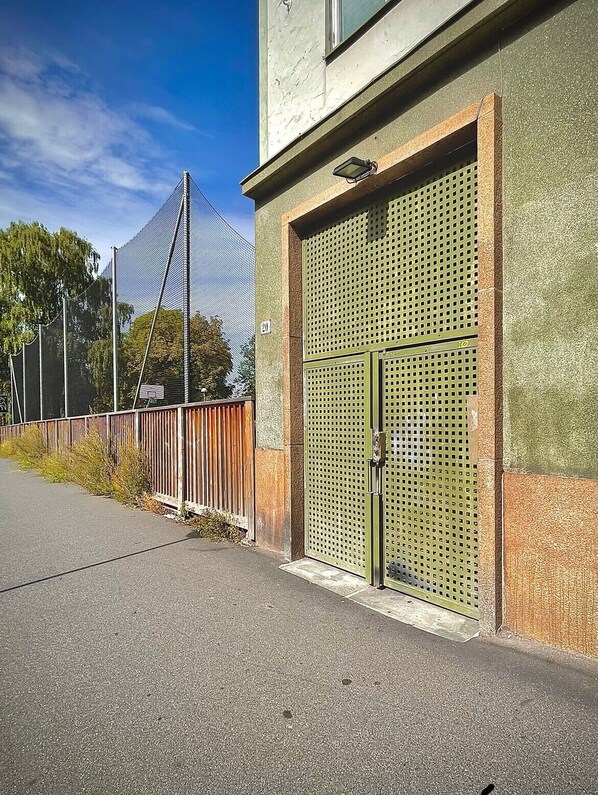 En bygning med en stor metalport og et indhegnet område med en høj struktur i baggrunden.