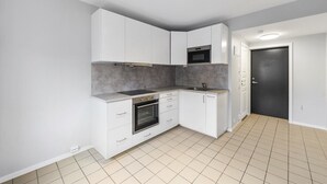 A modern kitchen with white cabinets, a built-in oven, and a microwave. - DOWNToWN KING BED FASHiONABLE (Oslo)