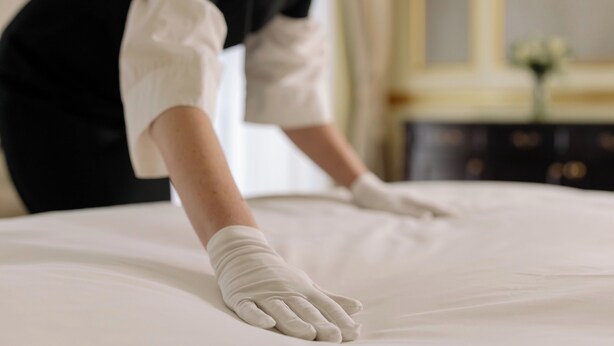 A person in a white shirt and black vest adjusting a bed. - DOWNToWN KING BED FASHiONABLE (Oslo)