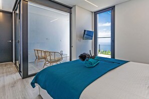 A modern bedroom with a large bed, a view of the outdoors, and a sliding glass door leading to a balcony. - Casa Juliana Teresa (Tijarafe)