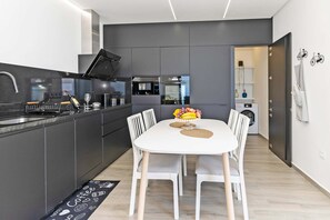 A modern kitchen with a white dining table, grey cabinetry, and a built-in oven. - Casa Juliana Teresa (Tijarafe)