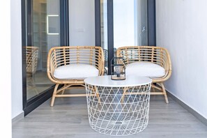 A room with two wicker chairs, a round table, and a geometric-patterned floor lamp. - Casa Juliana Teresa (Tijarafe)