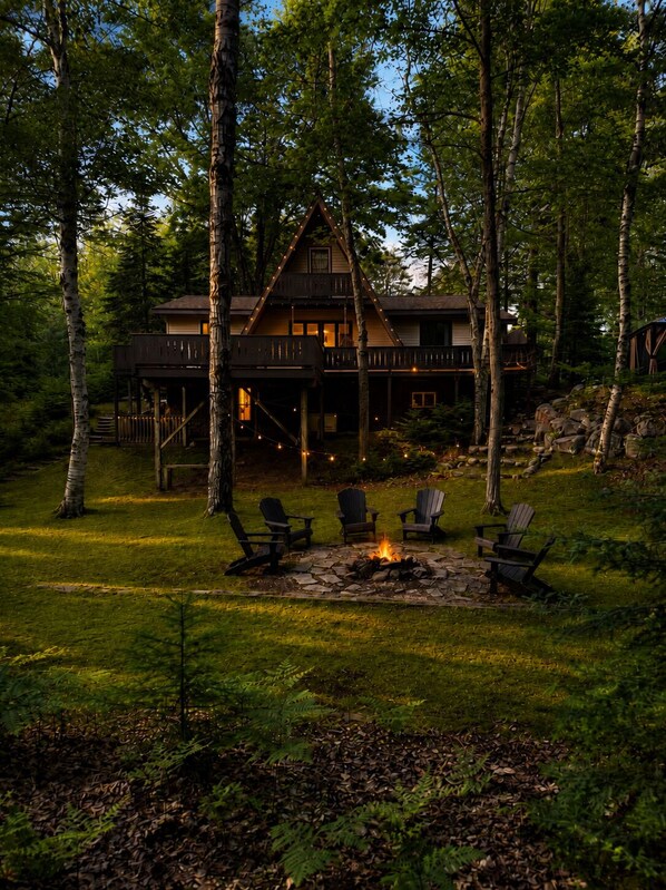 Une cabane avec un foyer et des sièges à l’extérieur.