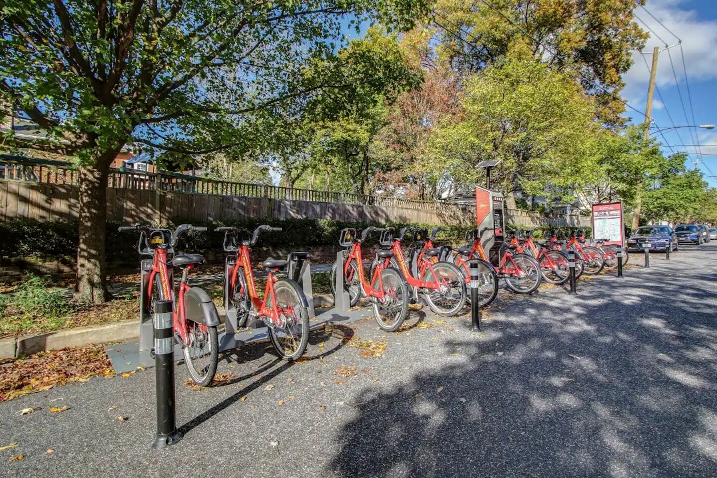 Une rangée de vélos rouges est stationnée devant un point de location de vélos en libre-service.