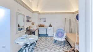 Una habitación compacta con una mesa de comedor, una silla, una pequeña cocina y una cama.