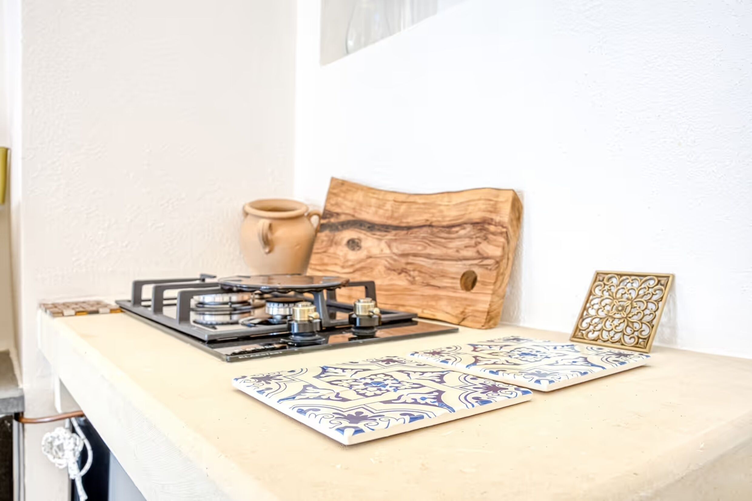 A kitchen counter with a gas stove, a wooden block, and a decorative tile.