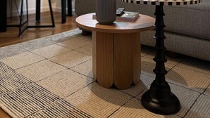 Un salon avec une table basse ronde en bois, un vase et un jeu d’échecs.