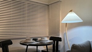 Un petit coin repas avec une table ronde, deux chaises et une lampe.
