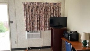 A room with a television on a wooden stand, a desk with a lamp, and a chair. - GULL LAKE LODGE MOTEL (Gull Lake)