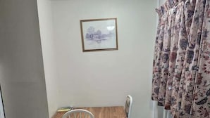 A small dining area with a wooden table and two chairs, a framed picture on the wall, and a window with floral curtains. - GULL LAKE LODGE MOTEL (Gull Lake)