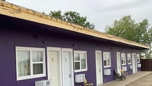 A row of single-story buildings with white-framed windows and doors, a flat roof, and a gravel ground. - GULL LAKE LODGE MOTEL (Gull Lake)