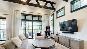 Een ruime woonkamer met een grote bank, een salontafel en een flatscreen televisie aan de muur.