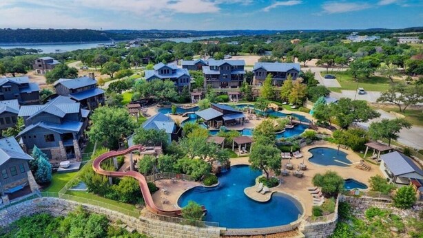 Een resort met meerdere gebouwen, een centraal gelegen zwembad en een glijbaan.