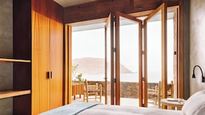 Un dormitorio con cama, armario de madera y balcón con mesa y sillas.