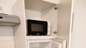 A compact kitchen with a built-in microwave, oven, and refrigerator.