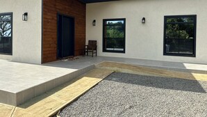 Ein modernes Gebäude mit Holzfassade, großen Fenstern und einer gepflasterten Terrasse.