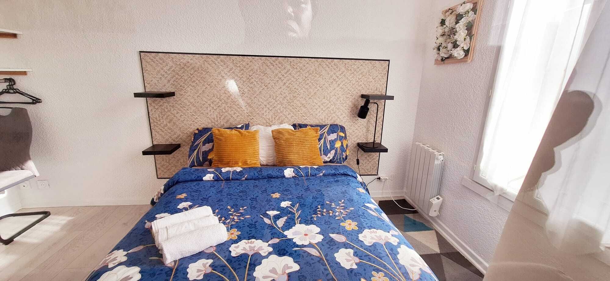 Et soveværelse med seng, radiator, et vindue og en vægmonteret hylde.