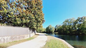 A pathway alongside a river with a metal fence on one side and trees on the other. - Attractive, renovated 2-room apartment by the lake (Saint-Jean-d'Angély)