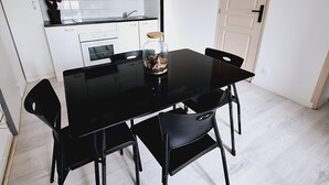 A compact kitchen with white cabinets, a black dining table, and four chairs. - Attractive, renovated 2-room apartment by the lake (Saint-Jean-d'Angély)