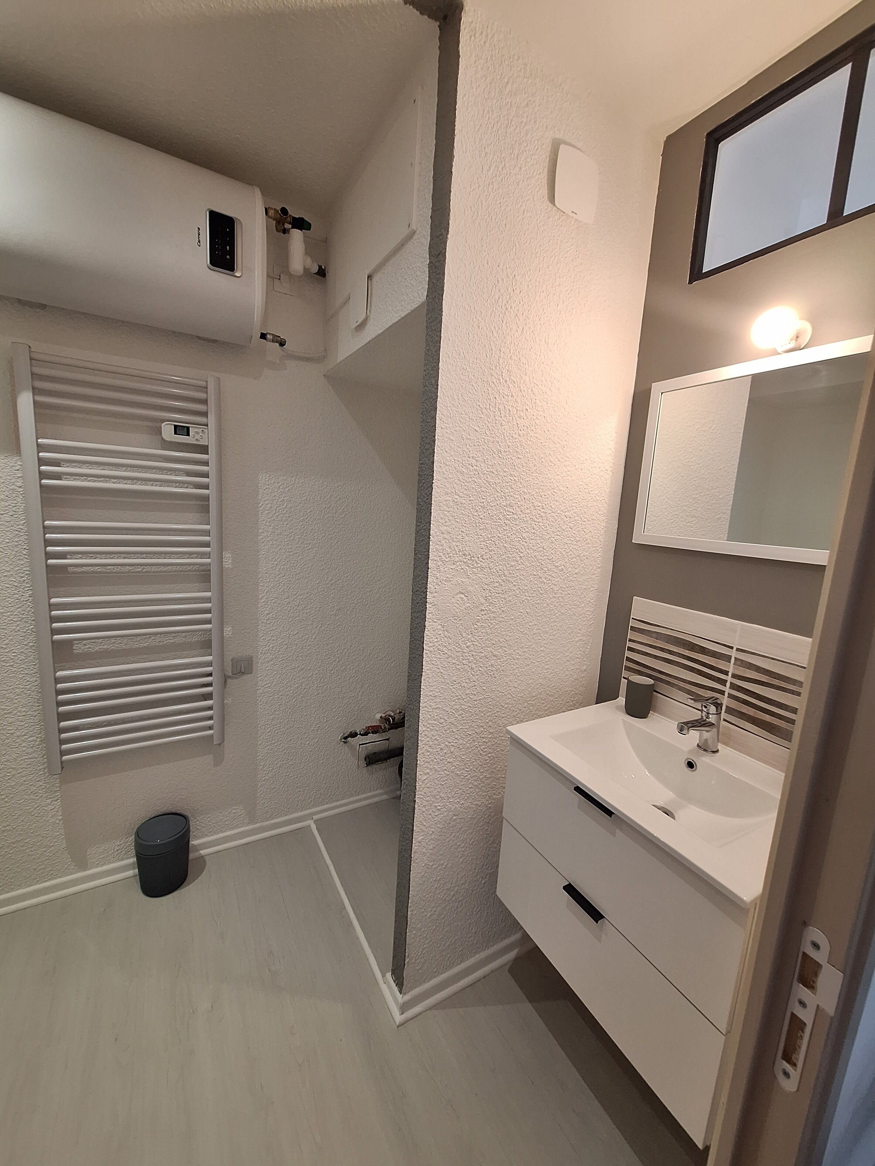 A bathroom with a white sink, mirror, and towel rack.