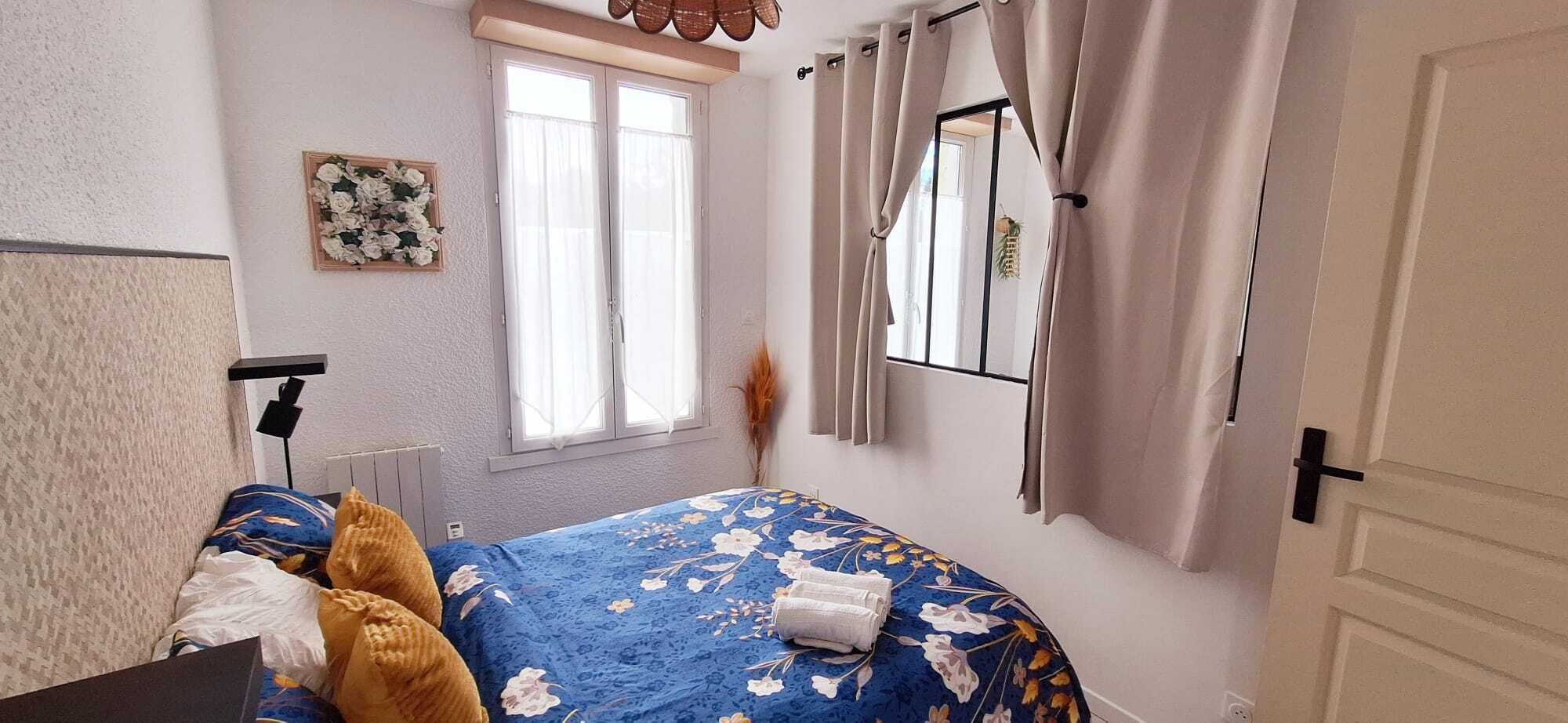 Une chambre à coucher avec un lit, une fenêtre, des rideaux, une porte et un miroir fixé au mur.