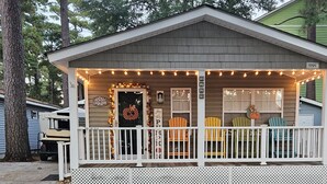 Uma casa pequena com varanda decorada com luzes e adornos temáticos de outono.