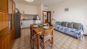 Une cuisine compacte avec une table à manger pour deux personnes, un canapé et un radiateur.