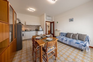 Una cocina compacta con una mesa de comedor preparada para dos personas, un sofá y un radiador.