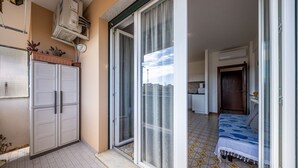 Une chambre comprenant un lit, une porte-fenêtre coulissante, un coin cuisine et un sol carrelé.
