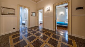 Un pasillo con suelo estampado, puertas que dan a un dormitorio y un espejo en la pared.