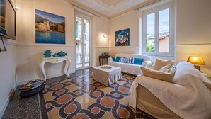 Una sala de estar con piso estampado, un sofá, una mesa de centro y un cuadro en la pared.