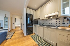 Eine moderne Küche mit weißen Schränken, einem Gasherd und einer gefliesten Spritzschutzwand.