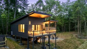 Une cabane en bois dotée d’un balcon, d’un porche couvert et d’un escalier menant à l’entrée principale.