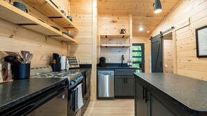 Une cuisine de taille réduite avec des murs en bois, une cuisinière, un lave-vaisselle et un évier.