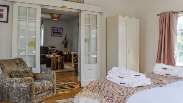 Habitació d'hotel amb llit, cadira, armari i escriptori amb cadira.